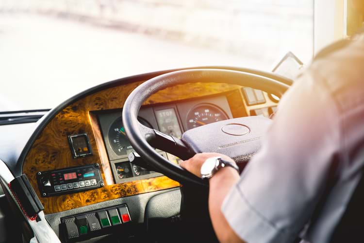 A male driver with his hands on the steering wheel of a railroad crew transportation shuttle