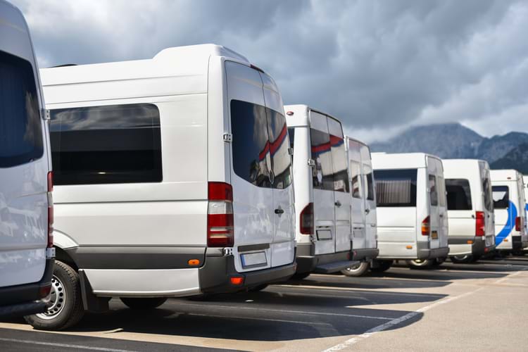 A row of parked white shuttles used by rail crew transportation services