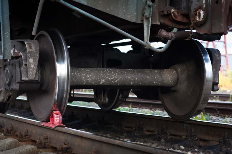 A red railway brake shoe under the train wheel on the rails