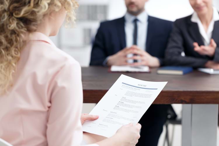 A man and a woman staffing for rail personnel by interviewing a young woman who is holding her resume