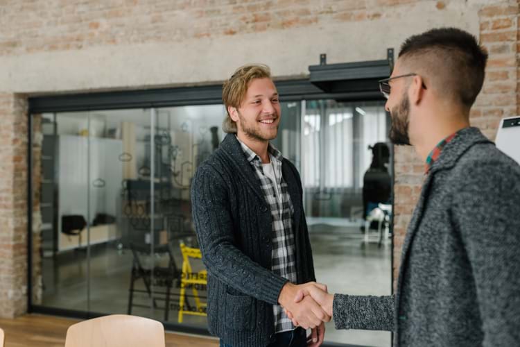 A young man openly greets a railroad job recruiter with a firm handshake